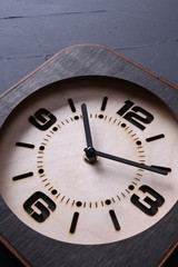 Wooden clock made in hand on wooden background. Close-up. Place for text.