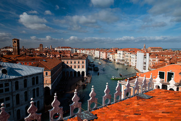 Fototapeta na wymiar Top view of the Grand Canal from the roof of a building in Venice. Orange roofs, gondolas and boats. Architecture and Tourism