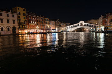 Night view of the city of Rialto and the Grand Canal. Buildings and night light reflect in the water. Venice, Italy