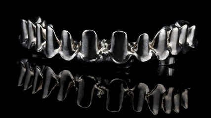 high-quality titanium beam for the manufacture of an upper jaw prosthesis, shot on black glass with reflection © Dental Pro Content