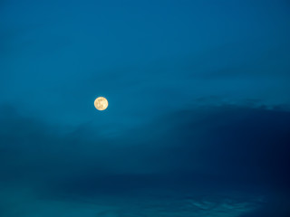 The moon at sunset, on the background the blue sky