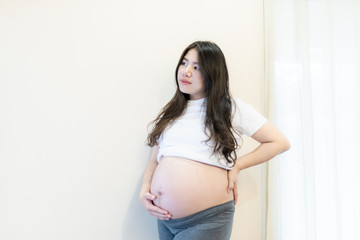 Pregnant woman feeling happy at home while taking care of her child. Maternity prenatal care and woman pregnancy concept.
