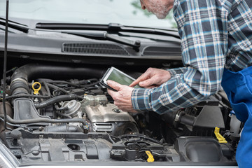 Fototapeta na wymiar Mechanic using digital tablet for checking car engine