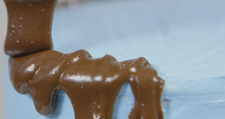 Soaking a blue cake with brown cream