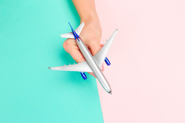  Beautiful young woman's hands holding plane    on pastel  background .