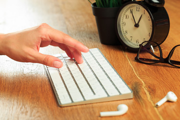 Female hands typing on white wireless modern keyboard  on wooden table   - Image