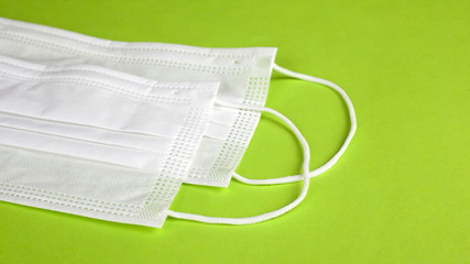 disposable medical white masks on a light green background close-up. flash protection coronavirus...