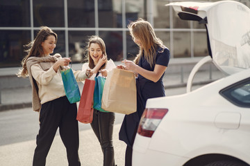 Girls on a shopping. Friends walks. Women with a shopping bags. Lady near trunk of the car.