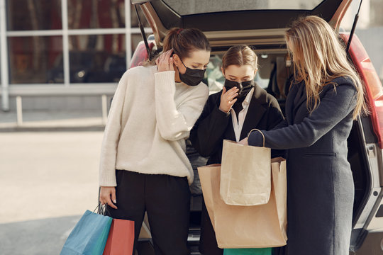 Girls on a shopping. People in a masks. Women with a shopping bags. Lady near trunk of the car. Coronavirus theme.