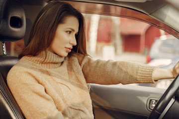 Fototapeta na wymiar Woman sitting in a car. Lady in a brown sweater.