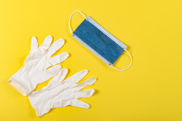 disposable medical mask and gloves on a yellow background