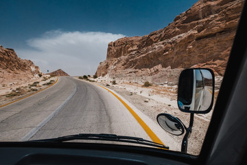Bus journey in Jordan . Travel by bus. Road in desert. Red rocks and stones. Bus tour. Tourism in a...