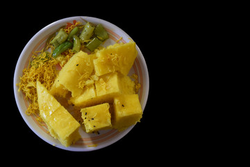 Khaman in plate with sev and mirchi with black background top view