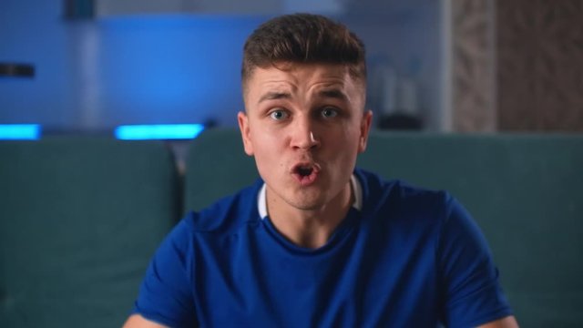 Man in fan hat with horns holding beer bottle, cheering for team and screaming in excitement as her favorite team scoring a goal.