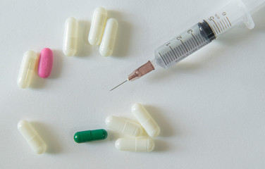 Vaccine syringe and have white, green pill capsules on white background