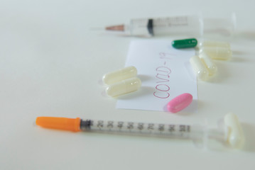 Red Covid-19 letter is placed between needle and capsule on white background.