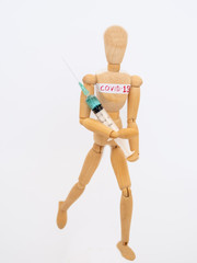COVID-19 Pandemic Coronavirus concept ; Close-up of a wooden model man is carrying syringe. Corona virus vaccine on the way.