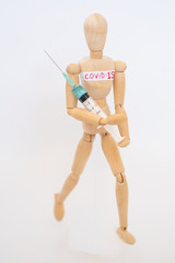 COVID-19 Pandemic Coronavirus concept ; Close-up of a wooden model man is carrying syringe. Corona virus vaccine on the way.