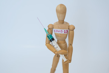 COVID-19 Pandemic Coronavirus concept ; Close-up of a wooden model man is carrying syringe. Corona virus vaccine on the way.