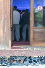 Shoes of praying people and praying people. Bolo Hauz Mosque. Bukhara, Uzbekistan.