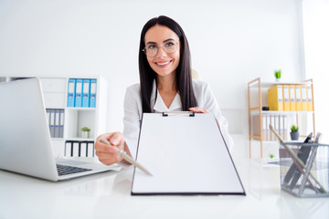Photo of beautiful professional doc lady hold clipboard with hospital contract insurance showing patient place for signature wear white lab coat sit chair office clinic indoors