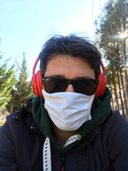 Fototapeta na wymiar COVID-19 Pandemic Coronavirus Man in city street wearing face mask protective for spreading of Coronavirus Disease. Selfie of man with surgical mask on face against SARS-CoV-2.