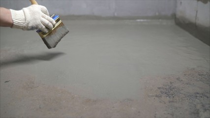 Waterproofing concrete mortar. The master puts waterproofing on a concrete floor with a brush.