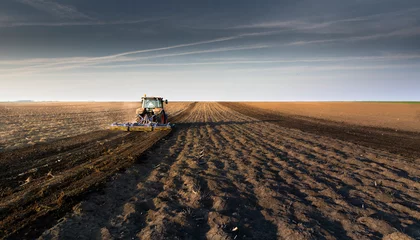 Fotobehang Tractor is preparing the land at dusk © Dusan Kostic