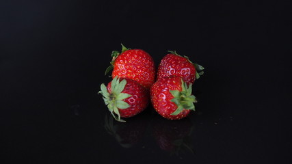4 strawberries on black background