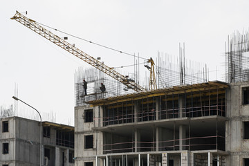 The construction of a multi-storey building. The crane. Concrete blocks. Metal carcass. Formwork. Large construction in the city