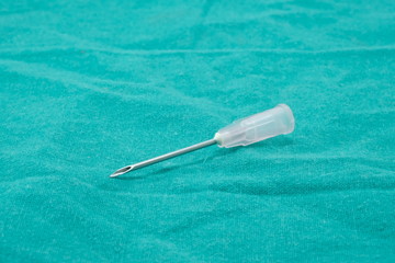 pink hypodermic needle or injection needle on a green blackground
