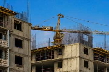  The construction of a multi-storey building. The crane. Concrete blocks. Metal carcass. Formwork. Large construction in the city