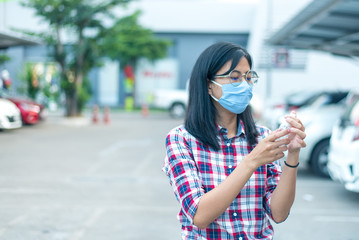 An Asian woman wears a surgical mask, walks through the mall, and a screening officer uses coronavirus to detect the body temperature before entering the mall.