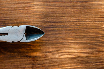 Labor day concept. Old repair tool pliers on brown color wooden background. Close up top view. Selective soft focus. Text copy space.