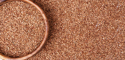 Raw roasted buckwheats and round wooden bowl. Russian grechka. Organic healthy diet food. Background for banner.