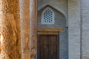 Old wooden pillars covered with carvings, details of decoration. Pahlavon Mahmud mausoleum, Khiva, Uzbekistan, Central Asia.