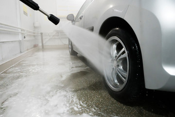 Man cleaning vehicle with high pressure water spray or jet. Car wash details. washing the rear...