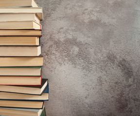 Time for yourself, the pleasure of reading. A vertical stack of books in close-up against a gray...