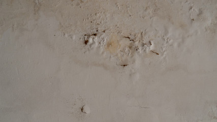 The surface of the old white wall and the color peeling off from the water stain