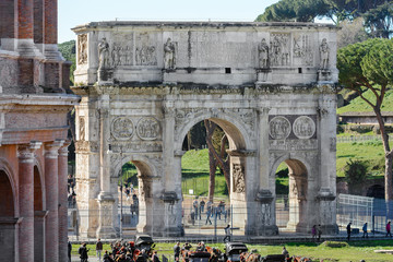Fototapeta na wymiar The Arch of Constantine is located next to the Colosseum in Rome. Via di San Gregorio street. The bas-reliefs of the arch were removed from other architectural structures. Three-span gate.