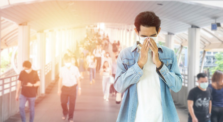 Naklejka premium Double Exposure image of Asian worker or business man wearing surgical mask hands covered her mouth while coughing with blurred of crowed,Wuhan coronavirus (COVID-19) outbreak pandemic prevention.