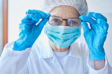 Woman as a doctor in protective clothing with a face mask