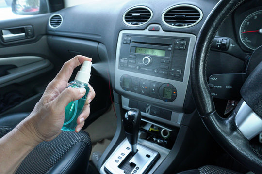 Hand of man is spraying alcohol,disinfectant spray in his car,prevent infection of Covid-19 virus,contamination of germs or bacteria,wipe clean surfaces that are frequently touched
