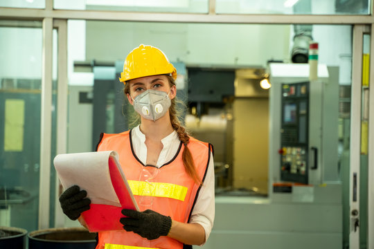 Female Mechanic wearing  protective mask to Protect Against Covid-19,Female technician worker working and checking machine in a large industrial factory,Coronavirus has turned into a global emergency