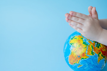 Children's hands pray,for planet Earth.
Concept of global problems of humanity.