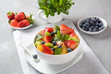 Bowl of healthy fresh colorful fruit salad on wooden background. Top view.Fruit salad with...
