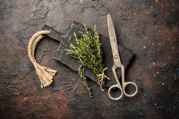 Fresh rosemary spice for tasty meals and scissors on black wooden board