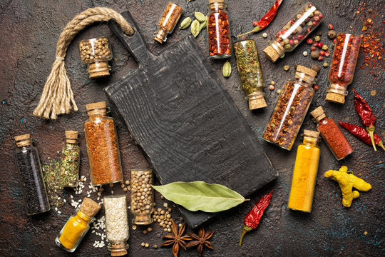Different spices, dry kitchen herbs and seeds in glass vials for tasty meals