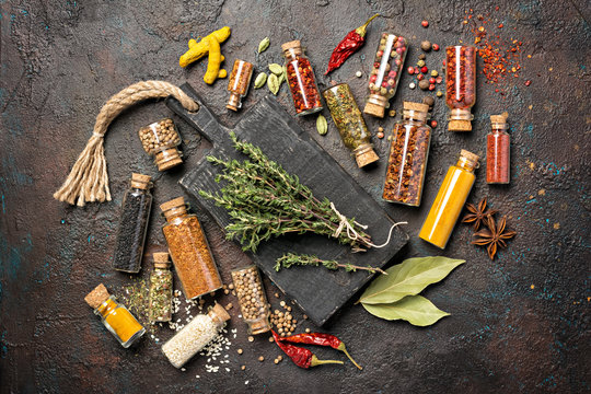 Different spices, dry kitchen herbs and seeds in glass vials for tasty meals