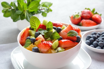 Bowl of healthy fresh colorful fruit salad on wooden background. Top view.Fruit salad with strawberry, blueberry, sweet cherry, kiwi.Vegetarian food concept. Rustic wooden background